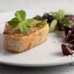 Swordfish Roasted Beet Parsnip Puree served on a white plate, sprinkled with micro greens and goat cheese