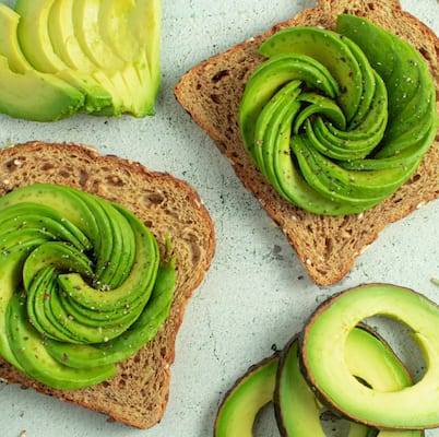 Avocado Flower Served on 2 pieces of whole grain toast with additional avocado slices around the toast