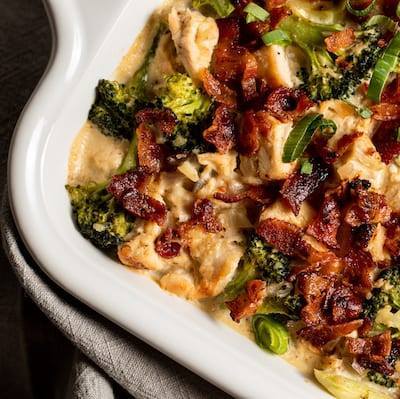 Broccoli, Bacon, and Chicken Casserole in a white dish with a grey napkin