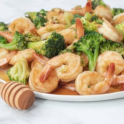 Honey Soy Broccoli and Shrimp served on a large white plate with a honey spoon next to it