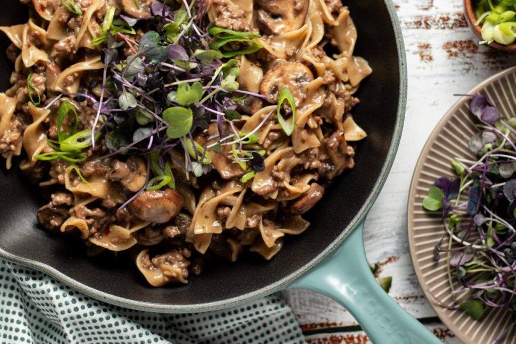 One Pot Beef Stroganoff Recipe, Noodles and beef cooked in a mushroom soup. Cooked in a light blue cast iron pan. Great for meal prep, counting macros, freezer friendly