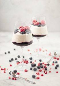 Healthy Blueberry Compote & Banana Yogurt Parfait served in a wine glass topped with frozen raspberries