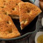Easy Cast Iron Focaccia Bread No Knead One hour Bread covered in herbs and cheese baked served in a pan.