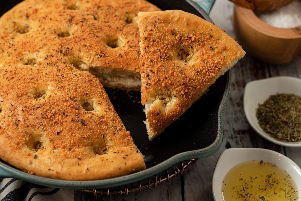 Easy Cast Iron Focaccia Bread No Knead One hour Bread covered in herbs and cheese baked served in a pan.
