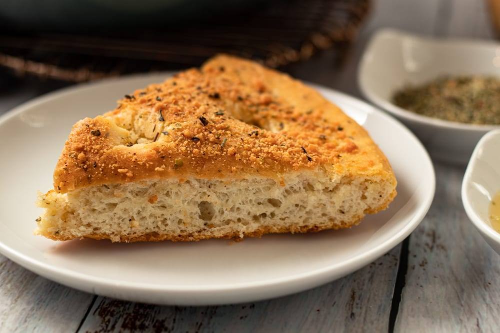 Easy Homemade Cast Iron Focaccia Bread No Knead One hour Bread covered in herbs and cheese baked served in a pan.