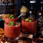 Easy The best gazpacho Recipe Thumbnail: Gazpacho served in glasses surrounded by chips on a round cutting board.